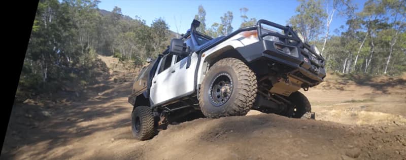 Weißes 4WD-Fahrzeug positioniert auf steiler sandiger Steigung in australischem Buschgelände demonstriert Offroad-Fähigkeiten