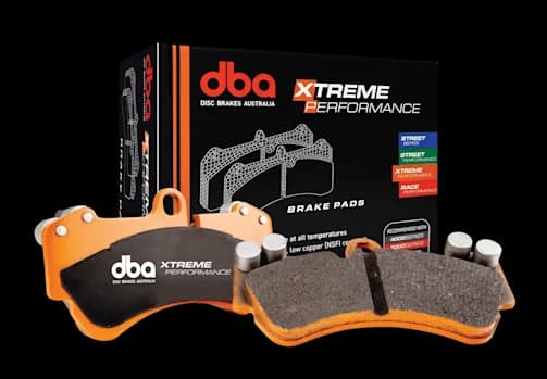 DBA Xtreme Performance Bremsbeläge mit orangefarbenen Trägerplatten und Reibmaterial neben der Verkaufsverpackung