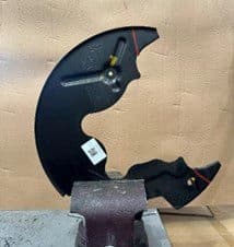 Schritt 3A: Vom Fahrzeug entfernte Ankerplatte im Schraubstock gesichert zum Schneiden entlang der markierten Linien für DBA-Bremssattelfreiraum Entfernte Ankerplatte im Schraubstock positioniert mit Farbstiftmarkierungen für Schnittlinien bereit zur Modifikation